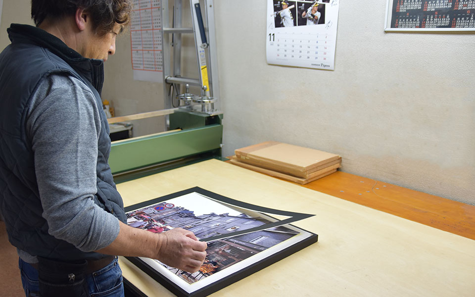 作業場で木製パネルに写真をはめるところ